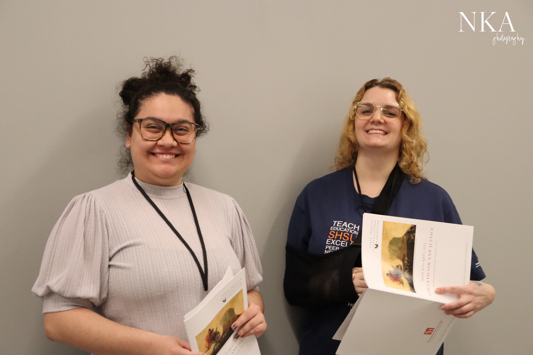 Two students smiling and holding programs at conference.